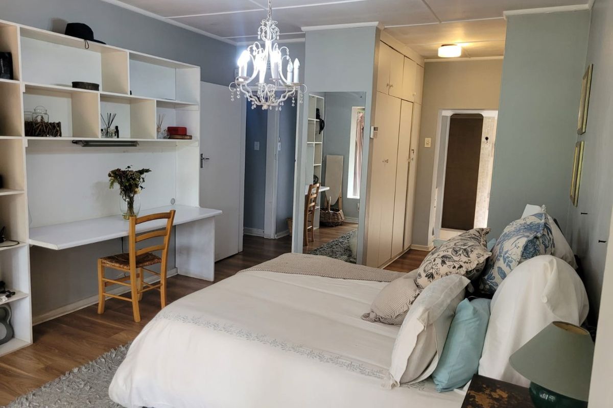 Spacious bedroom featuring built-in cabinetry, integrated desk workspace, and overhead chandelier lighting, providing a functional and well-organized living area.