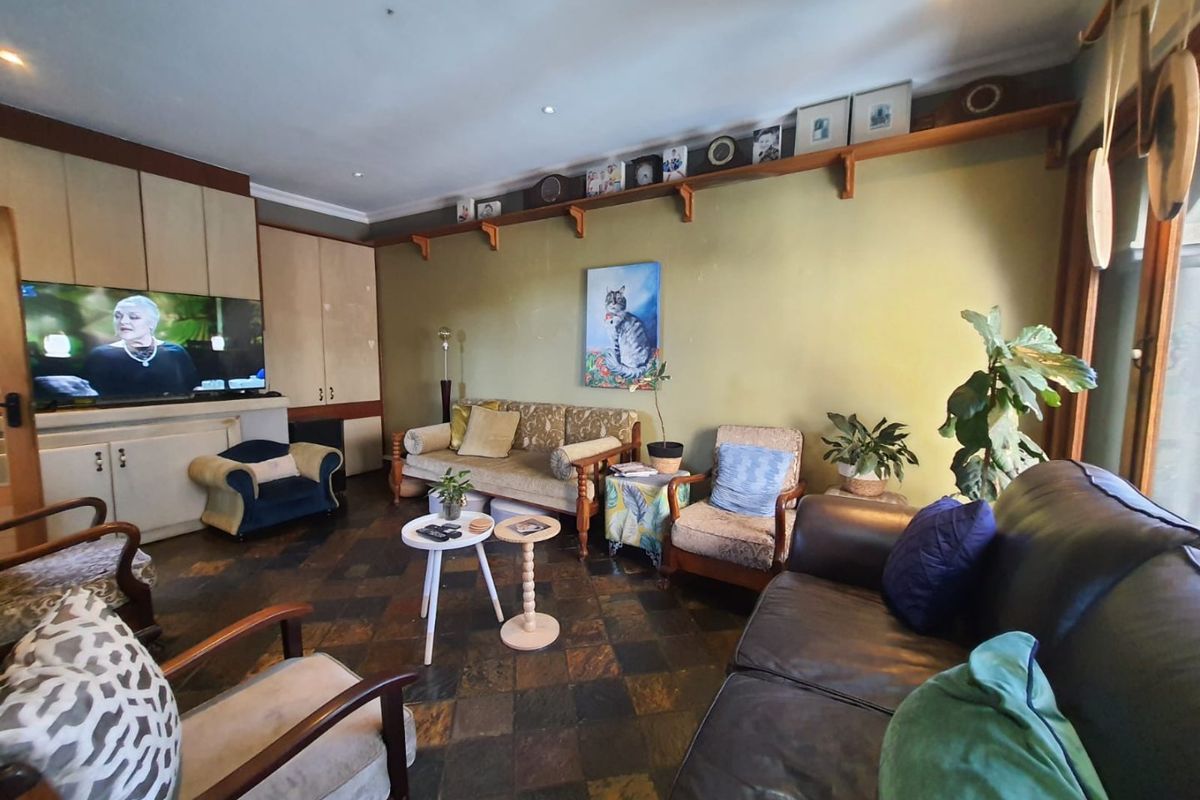 A spacious living room featuring built-in cabinetry, recessed ceiling lighting, and dark slate-style floor tiles.