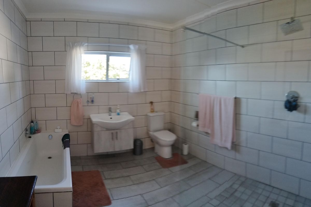 A spacious bathroom featuring a built-in bathtub, a separate walk-in shower, a vanity basin, and a toilet with neutral wall and floor tiling.