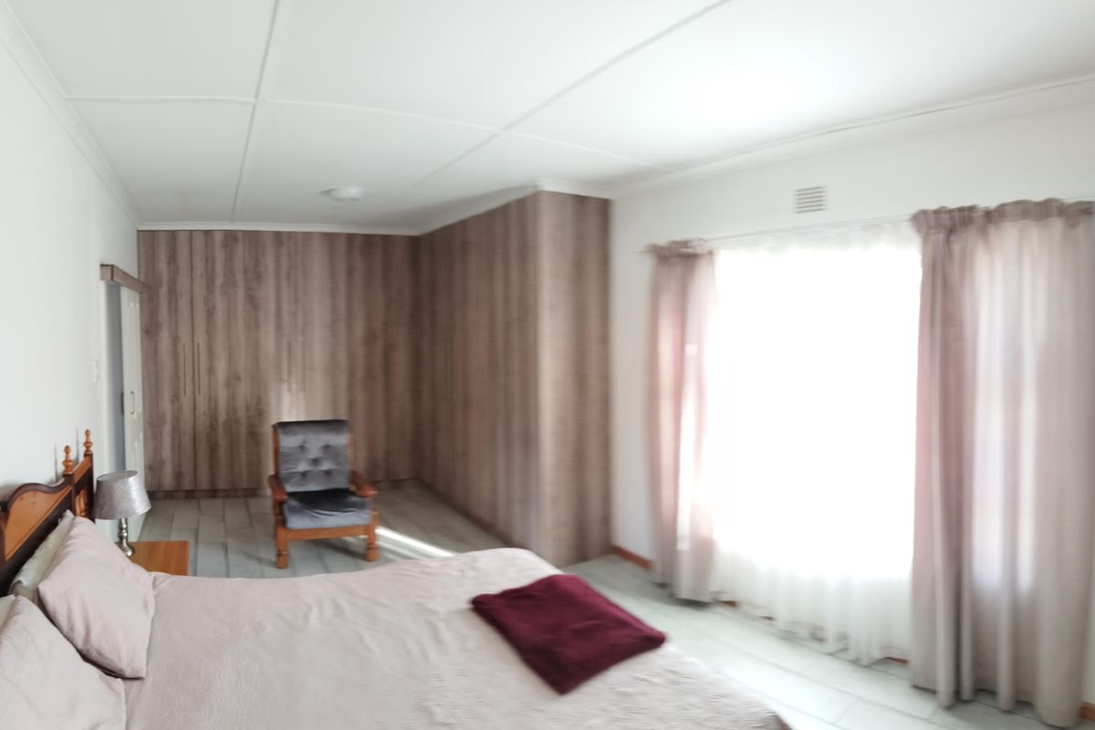 A bedroom featuring extensive built-in wooden cabinetry and large windows with curtains, providing ample storage and natural light.