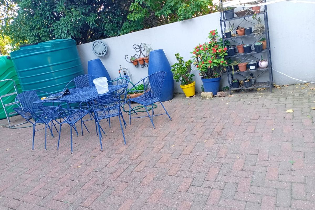 A paved rear patio area featuring large water storage tanks and a boundary wall, providing a functional outdoor space.