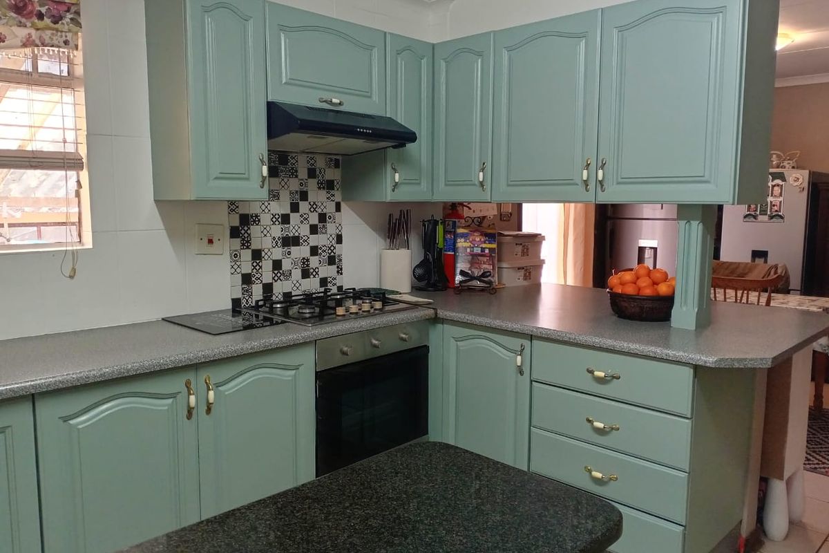 A functional kitchen featuring painted cabinetry, a gas hob with extractor fan, built-in oven, and durable laminate countertops with a decorative tiled backsplash.