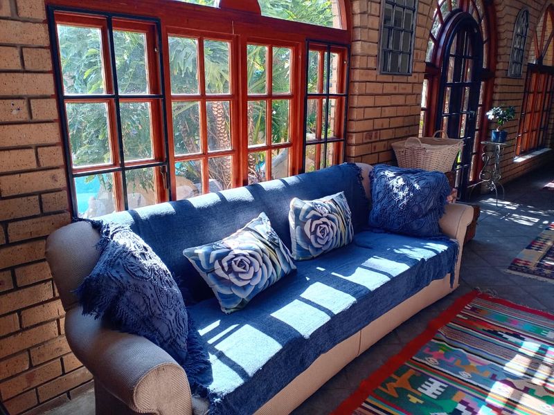 A living area featuring rustic exposed brick walls, large timber-framed windows, and tiled flooring, offering a warm and character-filled space.
