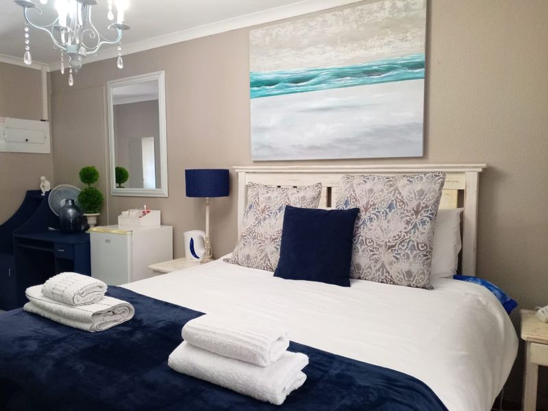 A well-maintained bedroom featuring neutral wall tones, a decorative ceiling light fixture, and a wall-mounted mirror.
