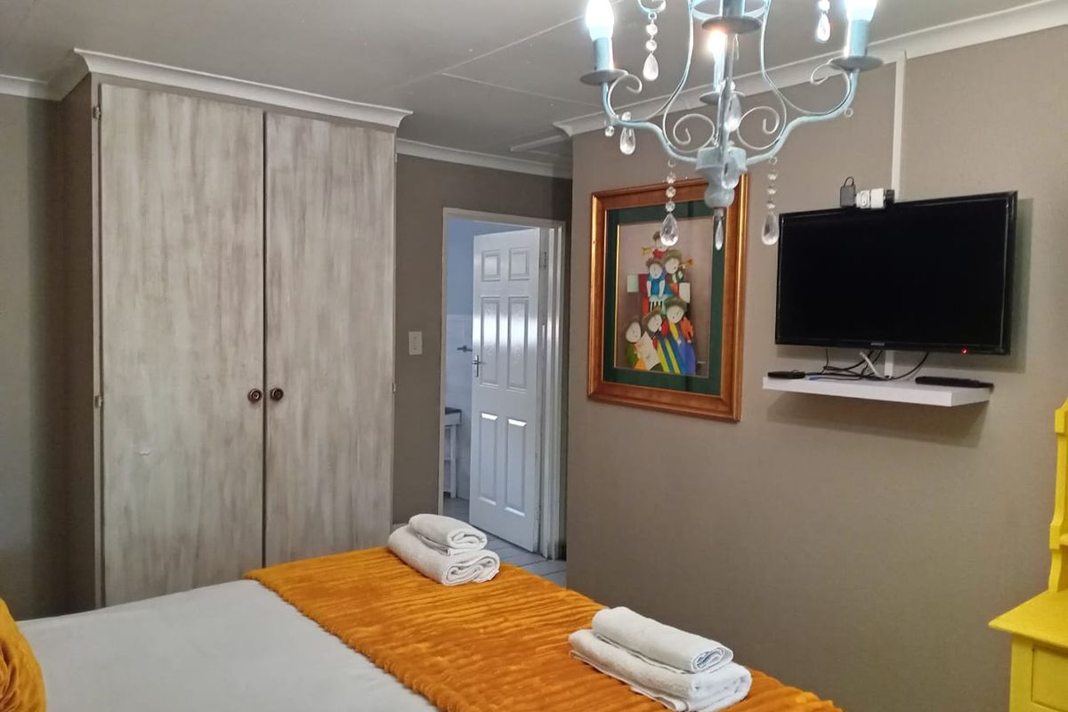A bedroom featuring a built-in wardrobe, neutral wall tones, and access to an adjoining room.