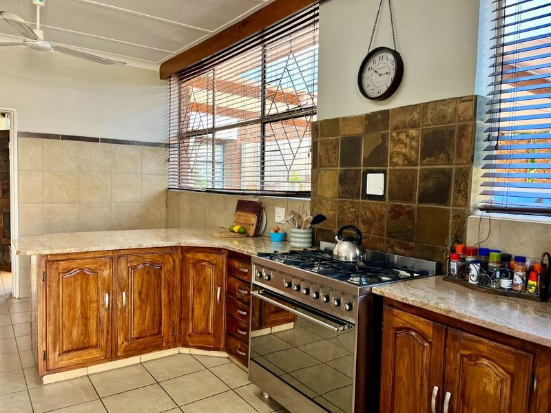 A functional kitchen featuring wooden cabinetry, granite countertops, a gas stove, and tiled splashbacks, offering a classic aesthetic with practical workspace.
