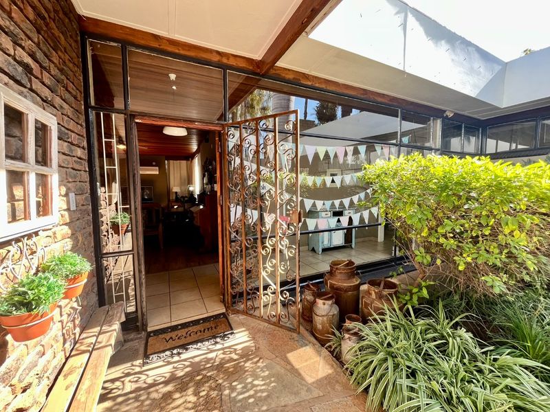 Entrance area featuring a rustic exposed brick wall, timber ceiling, tiled flooring, and a decorative wrought iron security gate leading into the home.