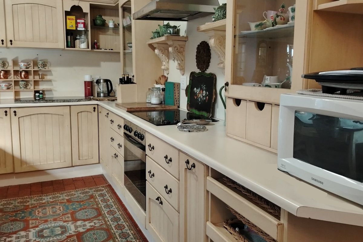 A traditional kitchen featuring cream-colored cabinetry, a built-in oven, a glass cooktop, and an extractor fan with decorative shelving.