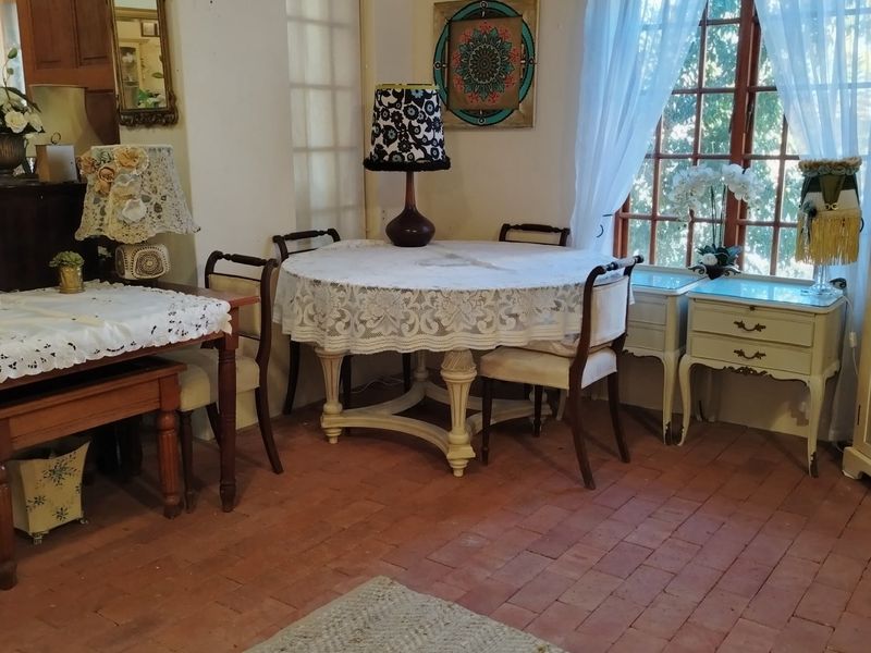 A dining area featuring traditional terracotta tile flooring and a large multi-pane window, providing a classic and rustic atmosphere.