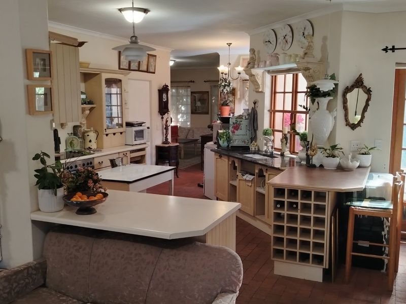A spacious open-plan kitchen featuring built-in cabinetry, a wine rack, and terracotta flooring, seamlessly connecting to the adjacent living area.