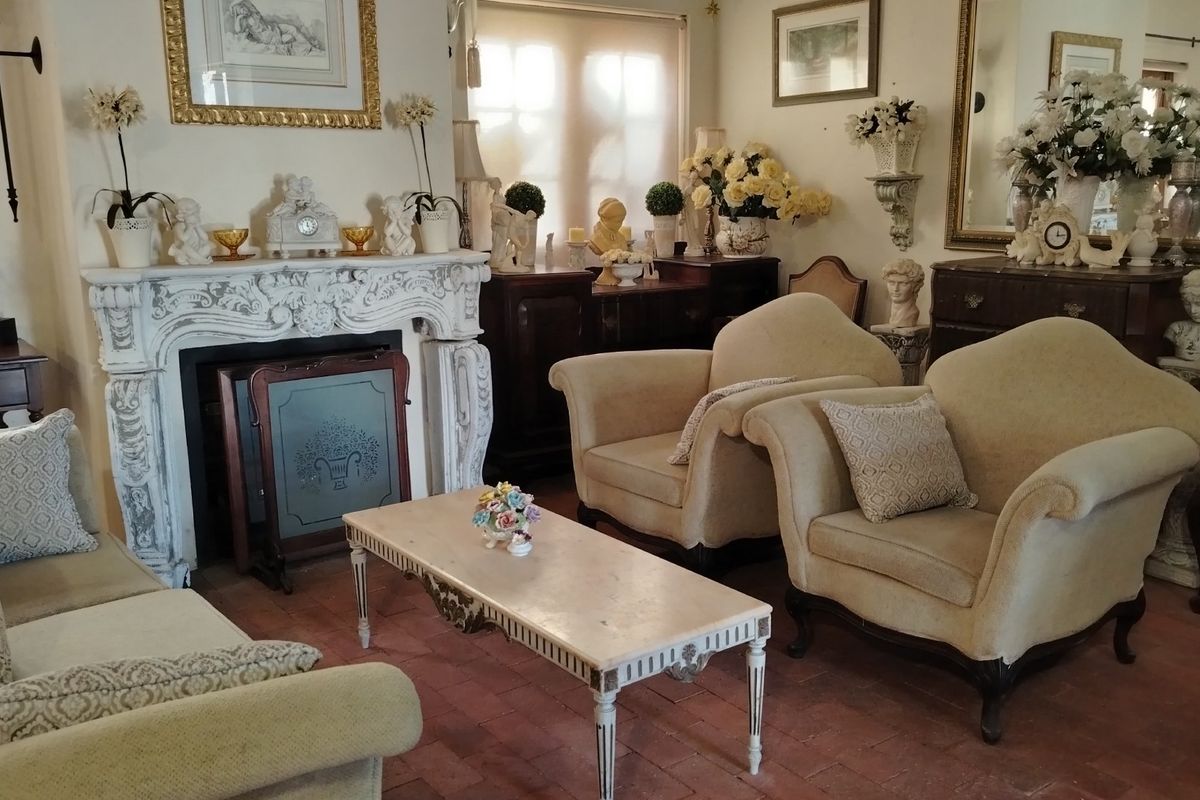 A traditional living room featuring a decorative carved stone fireplace surround and terracotta tile flooring.