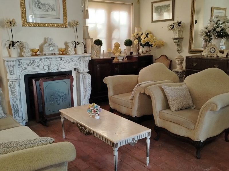 A traditional living room featuring a decorative carved stone fireplace surround and terracotta tile flooring.