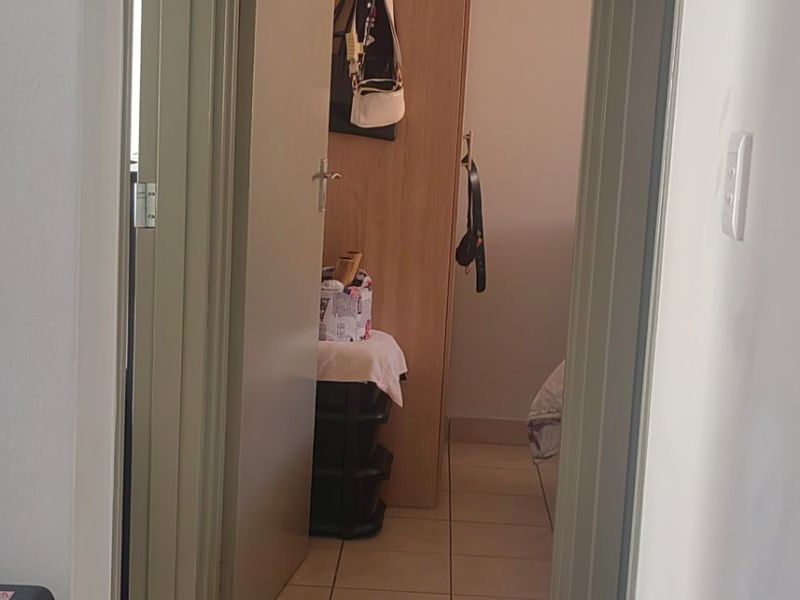 A functional hallway featuring tiled flooring and access to a bedroom with a built-in cupboard.