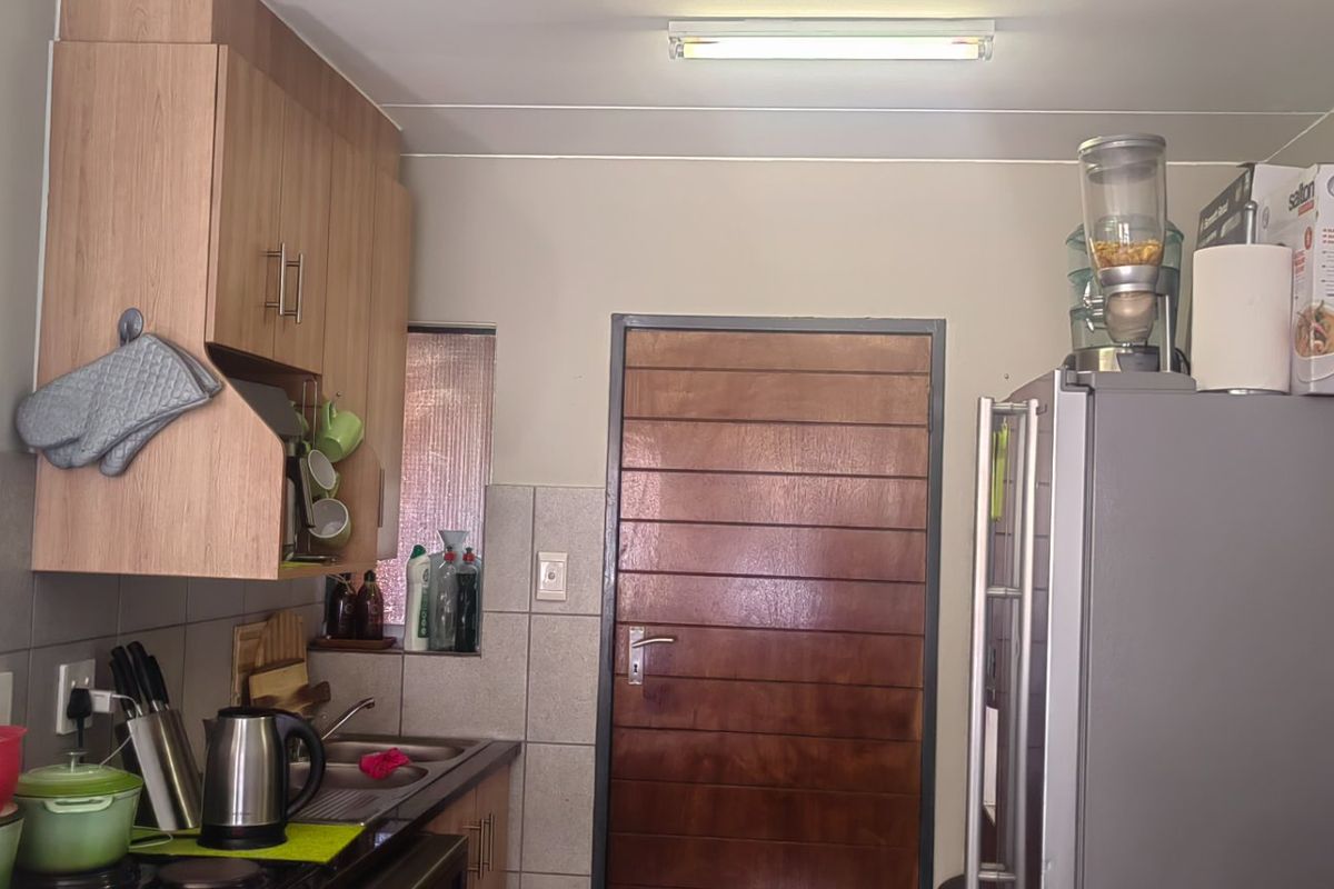 A functional kitchen area featuring built-in wooden cabinetry, a tiled backsplash, and a stainless steel sink, providing a practical workspace.