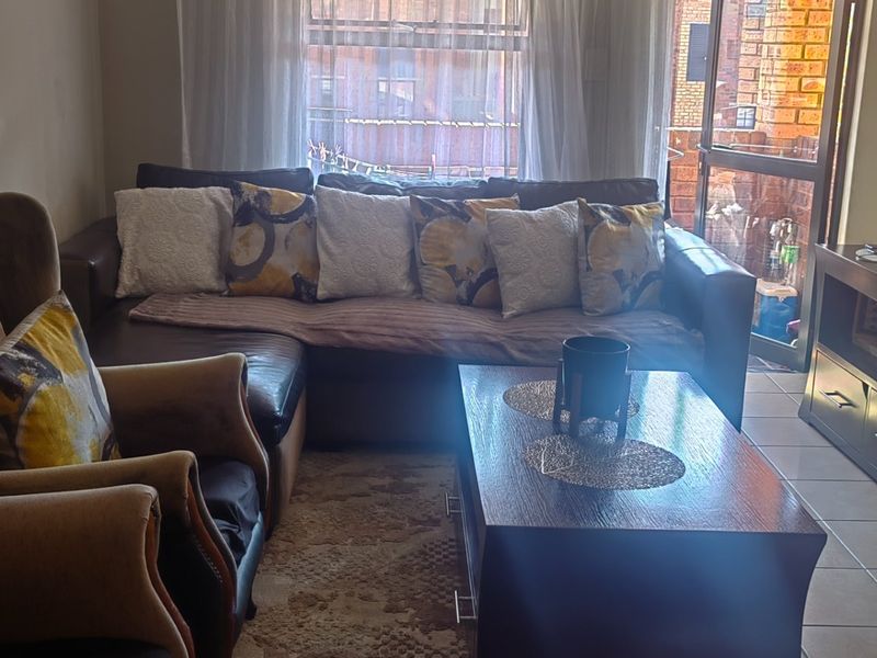 A compact living room featuring tiled flooring and a sliding glass door providing access to an outdoor area.