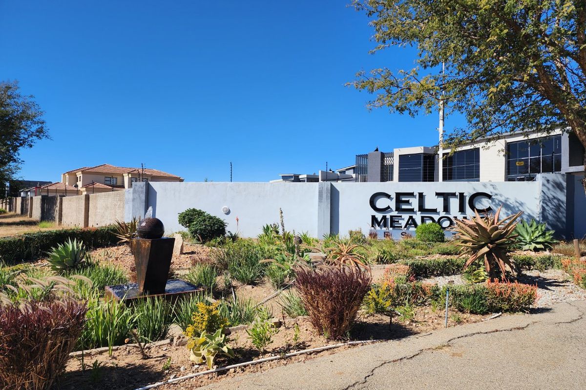 Front entrance view of Celtic Meadows estate featuring a prominent boundary wall, estate signage, and a landscaped garden with a water feature.