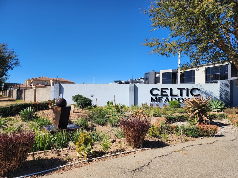Front entrance view of Celtic Meadows estate featuring a prominent boundary wall, estate signage, and a landscaped garden with a water feature.