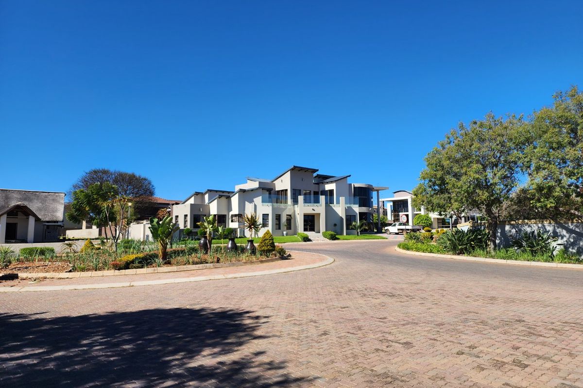 A clear street-level view of a modern, multi-level residential property featuring paved driveway access and established landscaping.