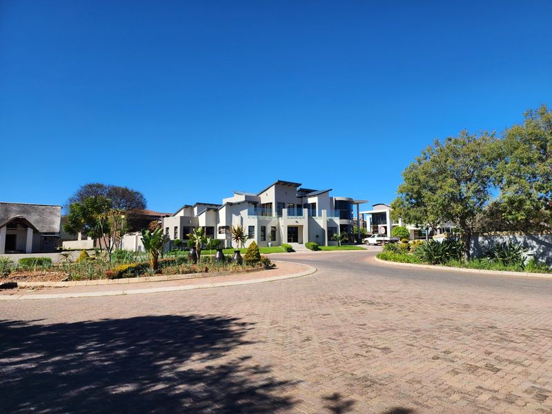 A clear street-level view of a modern, multi-level residential property featuring paved driveway access and established landscaping.