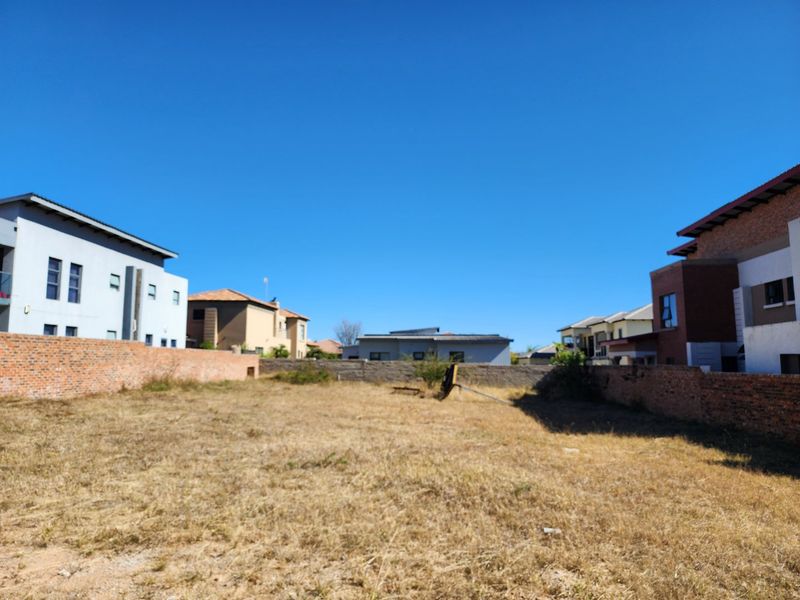 A vacant residential plot enclosed by brick boundary walls, situated within a developed neighborhood setting.