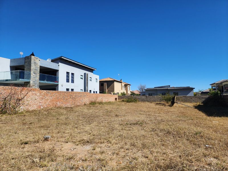 A vacant residential plot featuring established brick and concrete boundary walls, situated in a developed neighborhood.