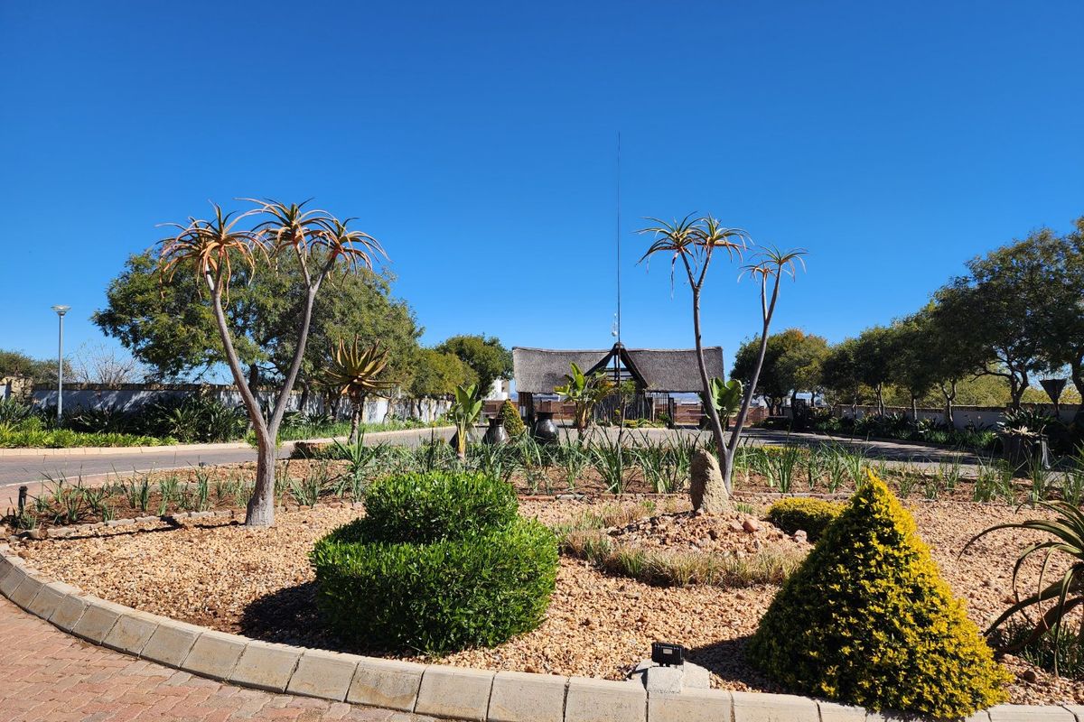 A well-maintained landscaped garden area featuring paved pathways, established trees, and decorative shrubs within a residential estate setting.
