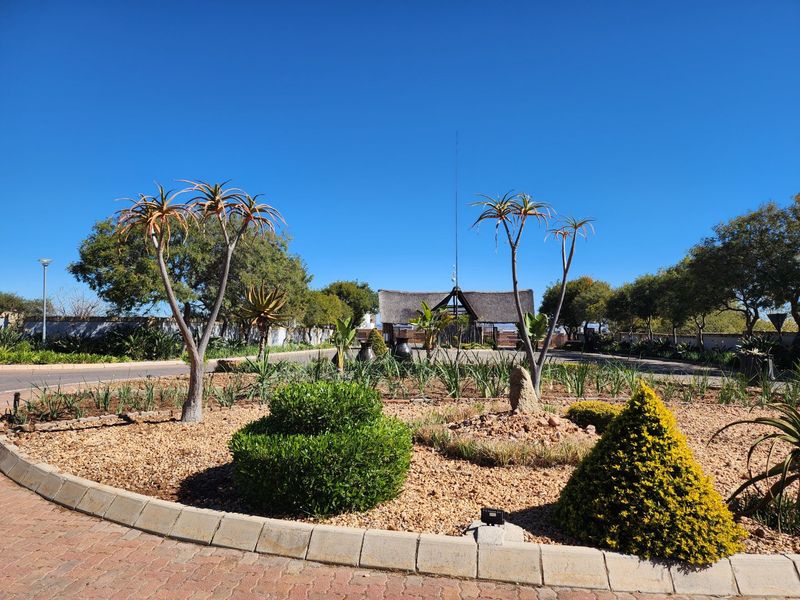 A well-maintained landscaped garden area featuring paved pathways, established trees, and decorative shrubs within a residential estate setting.