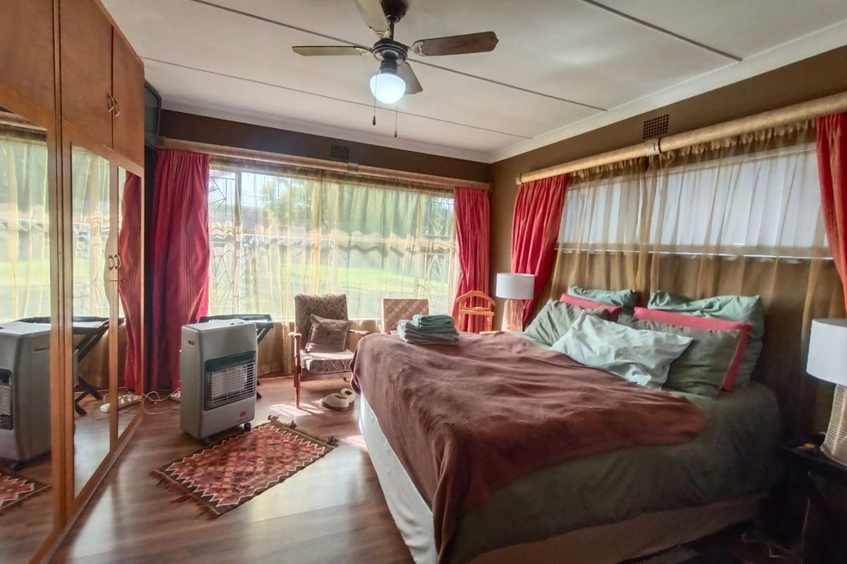 Spacious bedroom featuring large built-in mirrored wardrobes, a ceiling fan, and expansive windows allowing for natural light.