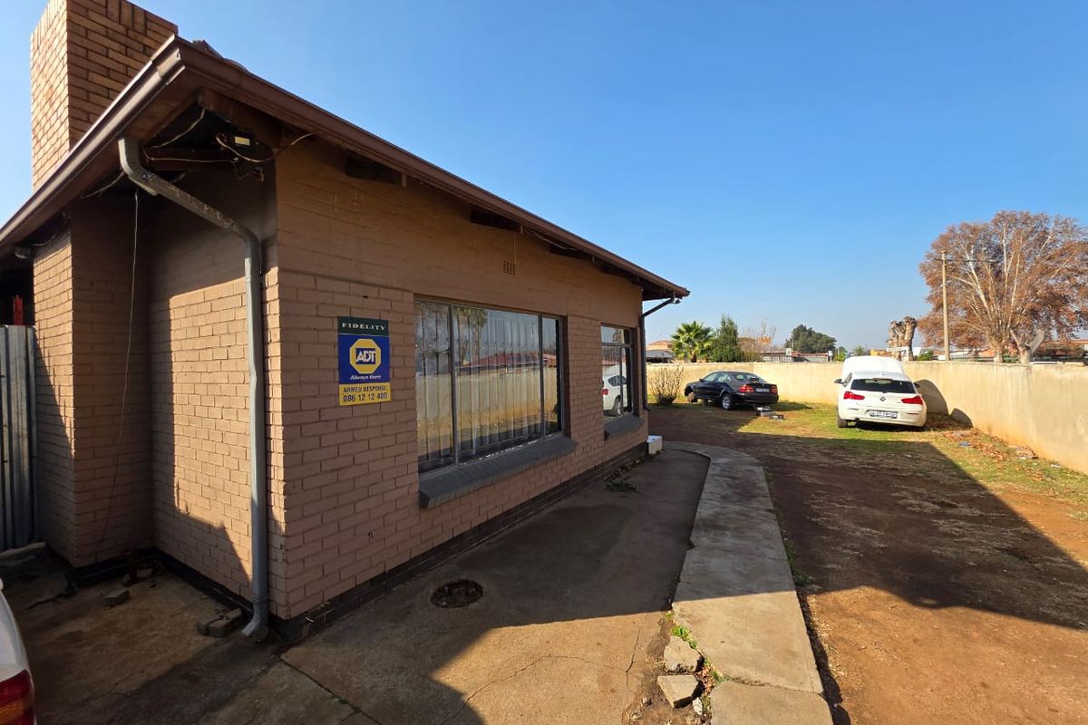 Exterior view of the property showing brick facade, concrete pathway, and surrounding yard area.