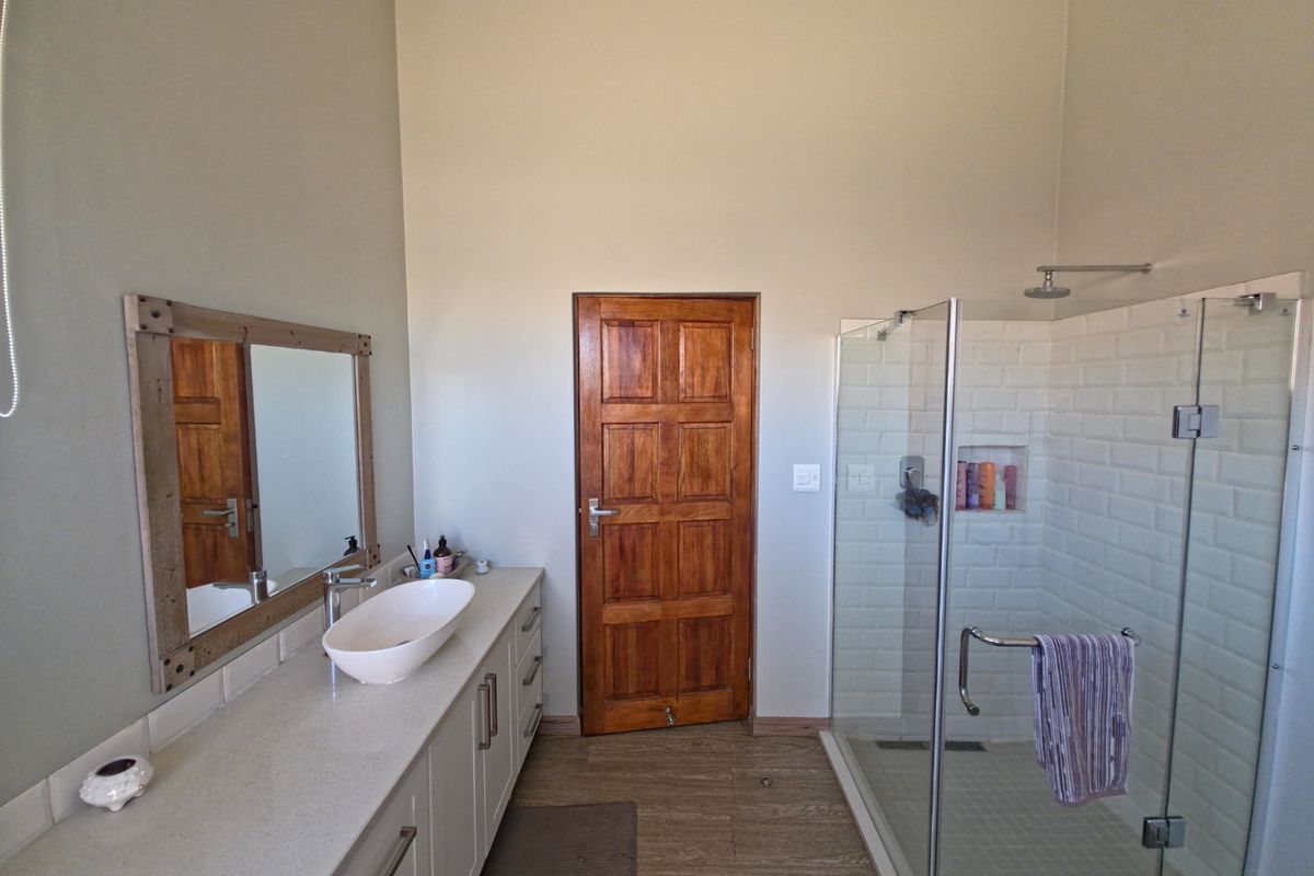 A modern bathroom featuring a vanity with a vessel sink, a walk-in shower with subway tile surround, and a solid wood door.