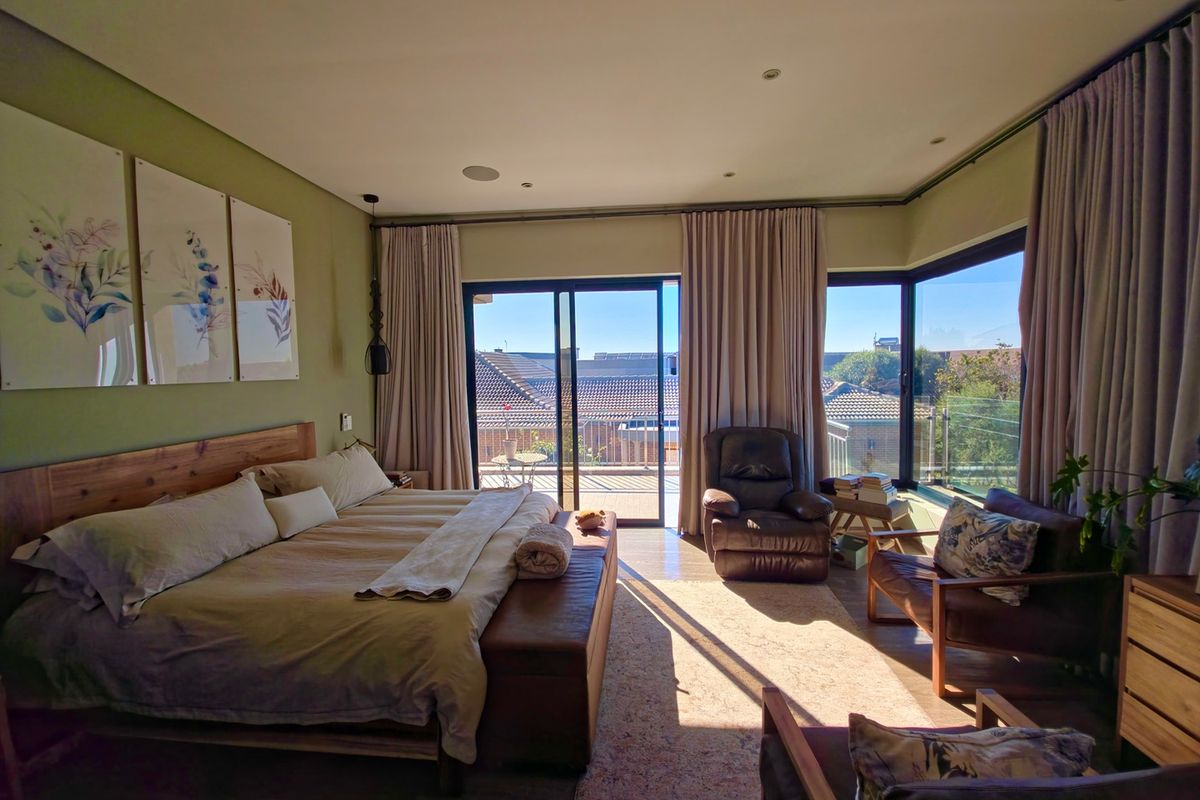Spacious bedroom featuring large sliding glass doors leading to a private balcony, recessed ceiling lighting, and neutral wall finishes.