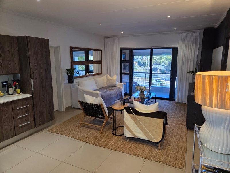 Modern open-plan living area featuring tiled floors, recessed lighting, and seamless access to a private balcony through large sliding glass doors.