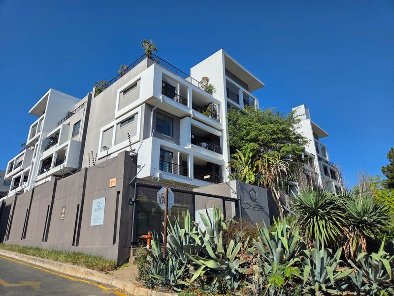 Modern multi-story apartment complex featuring contemporary architectural design, secure perimeter walling with electric fencing, and landscaped garden areas.
