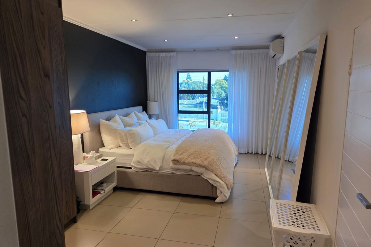 A well-maintained bedroom featuring tiled flooring, recessed lighting, an air conditioning unit, and built-in storage with a large window providing natural light.