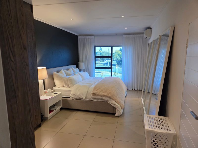 A well-maintained bedroom featuring tiled flooring, recessed lighting, an air conditioning unit, and built-in storage with a large window providing natural light.