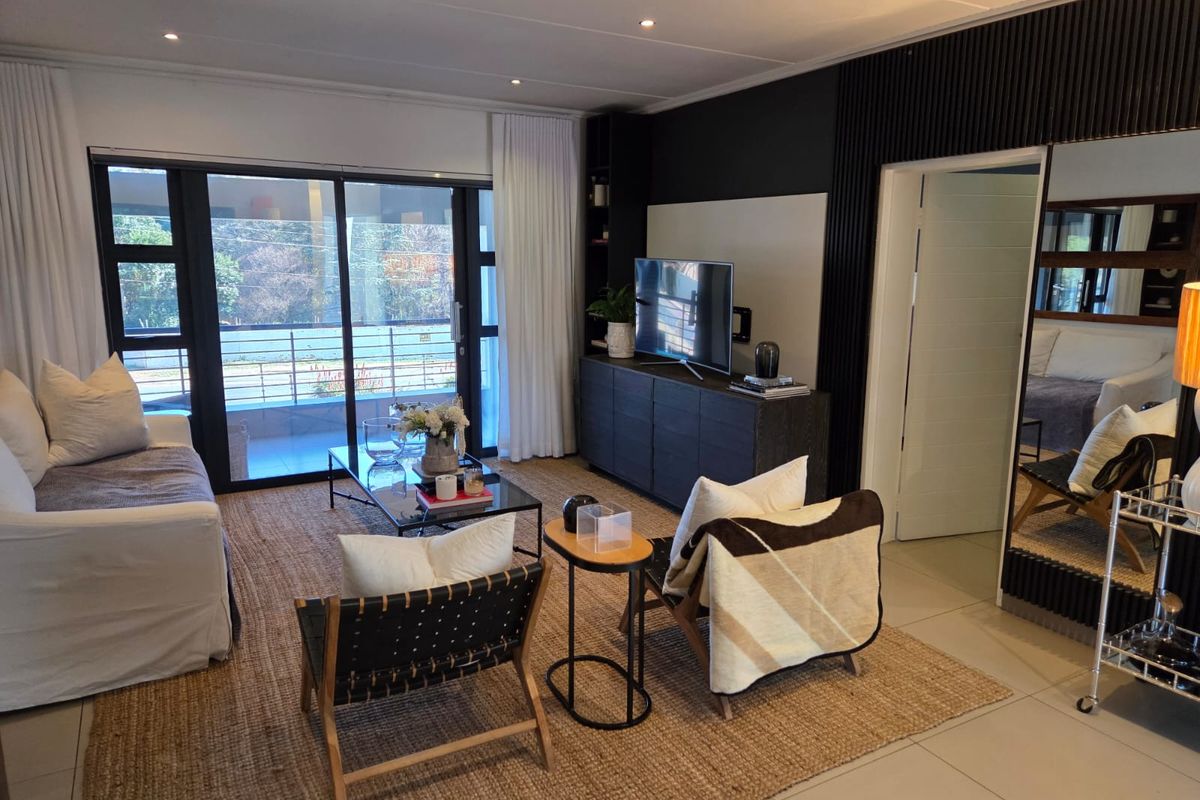 Modern living room featuring tiled floors, recessed lighting, and a stylish dark feature wall with integrated shelving and sliding doors leading to a balcony.