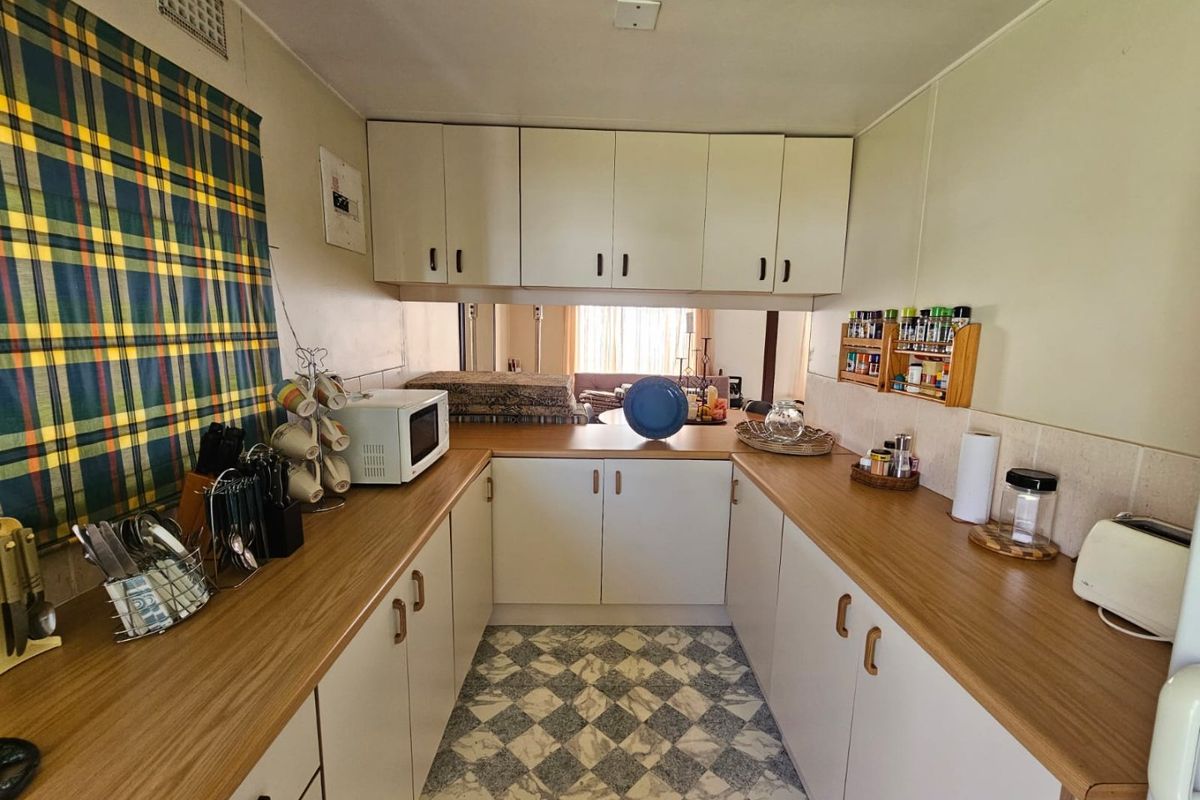 A functional U-shaped kitchen featuring laminate countertops, white cabinetry, and patterned vinyl flooring, offering a practical layout with ample storage space.