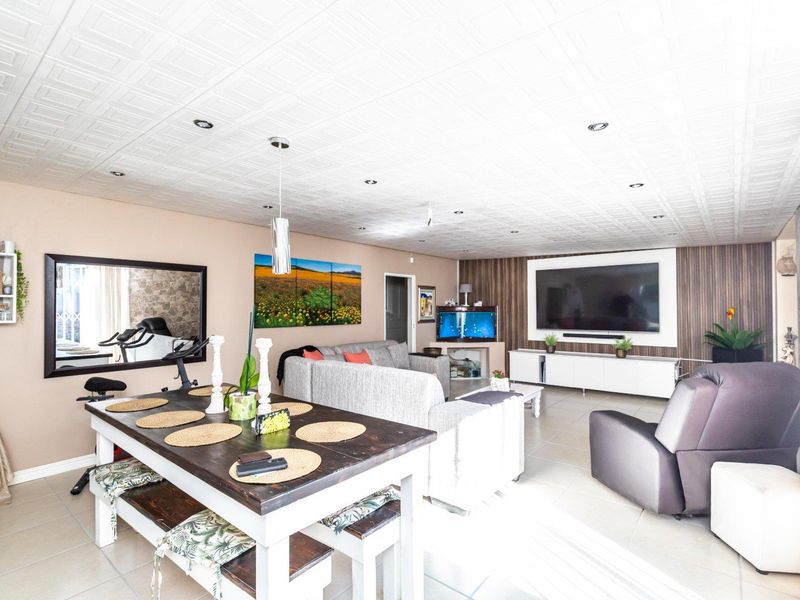 Spacious open-plan living area featuring tiled flooring, a textured ceiling with recessed lighting, and a dedicated built-in media wall unit.