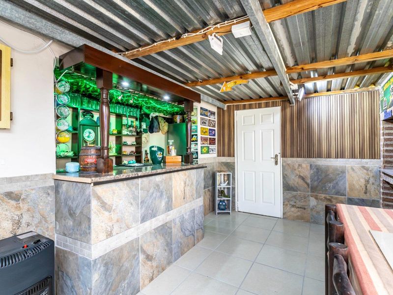 A dedicated indoor bar area featuring a built-in counter, tiled wall finishes, and a rustic corrugated metal ceiling with exposed timber beams.