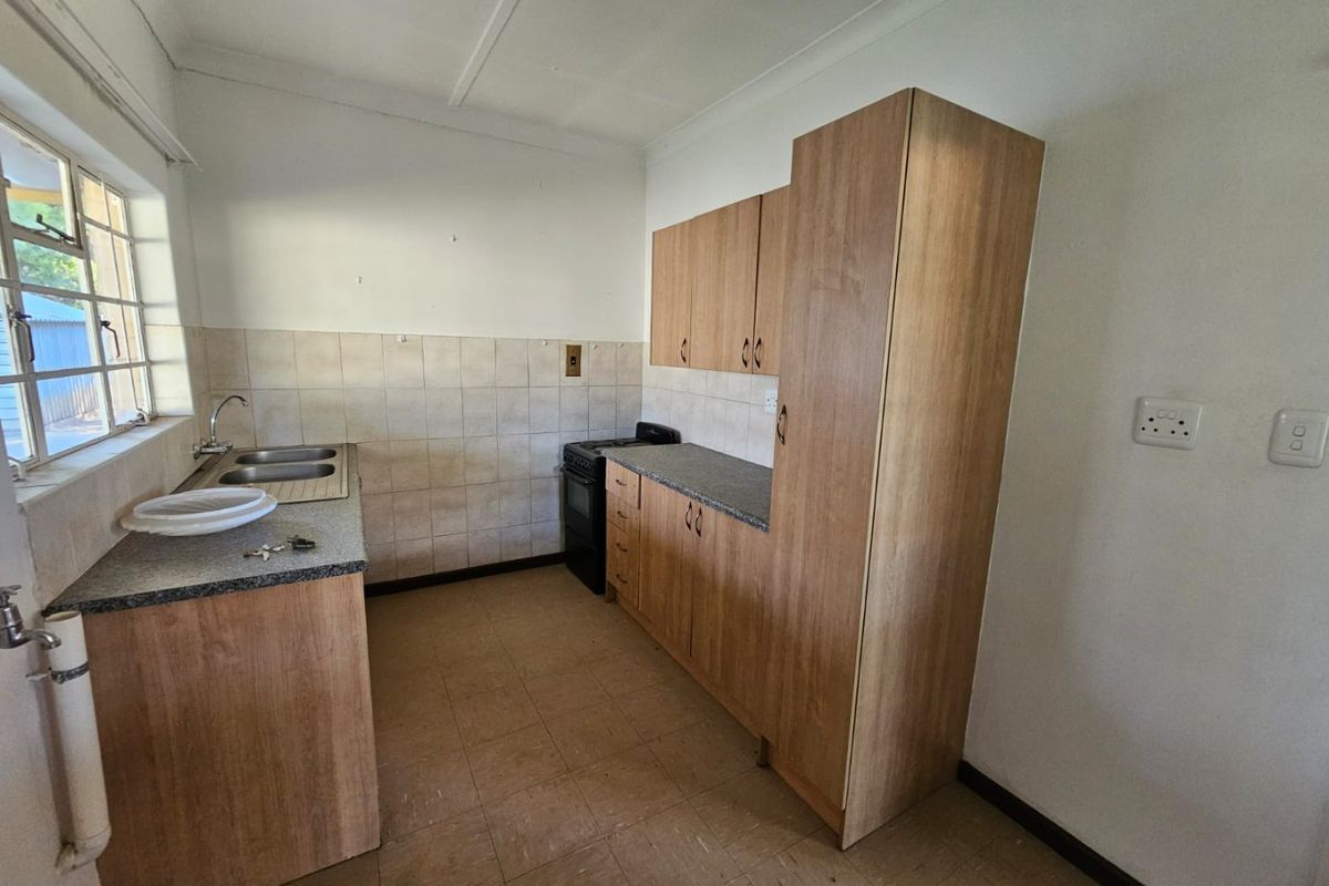 A functional kitchen featuring wood-look cabinetry, laminate countertops, a double-basin sink, and a freestanding stove, offering a practical layout for daily use.