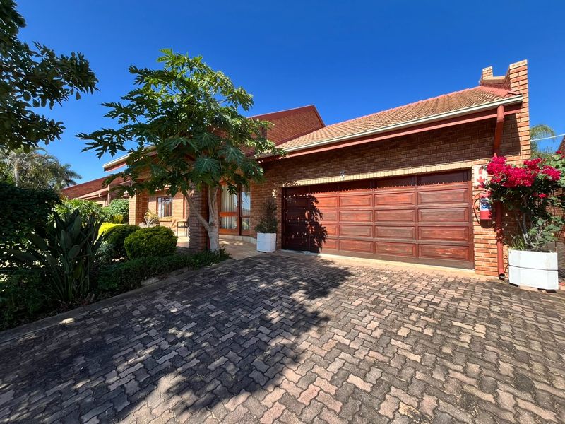 Front elevation of a brick house featuring a paved driveway, a wooden garage door, and a covered entrance area.
