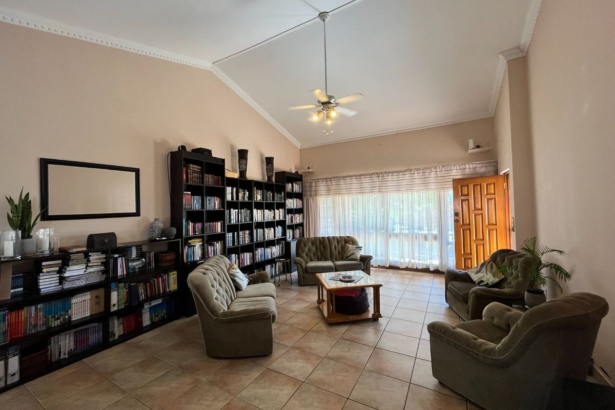 Spacious living room featuring vaulted ceilings, crown molding, tiled flooring, and extensive built-in shelving, offering a comfortable and functional living space.