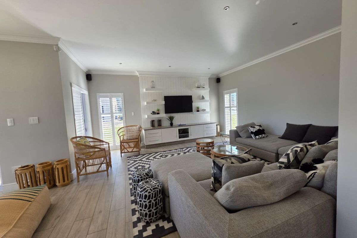 Spacious living room featuring wood-look tile flooring, recessed lighting, and a custom built-in media unit with shelving and cabinetry.