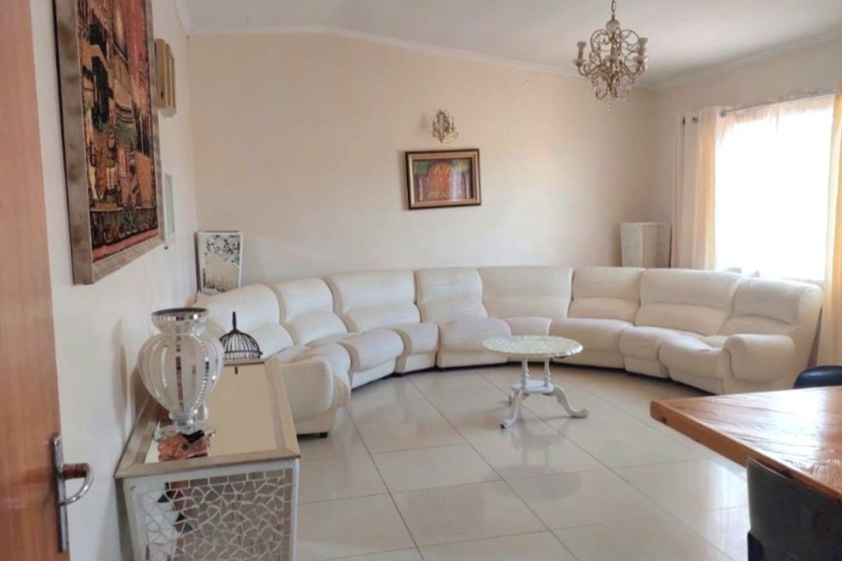 Spacious living room featuring large format floor tiles, a decorative chandelier, and coved ceiling details.