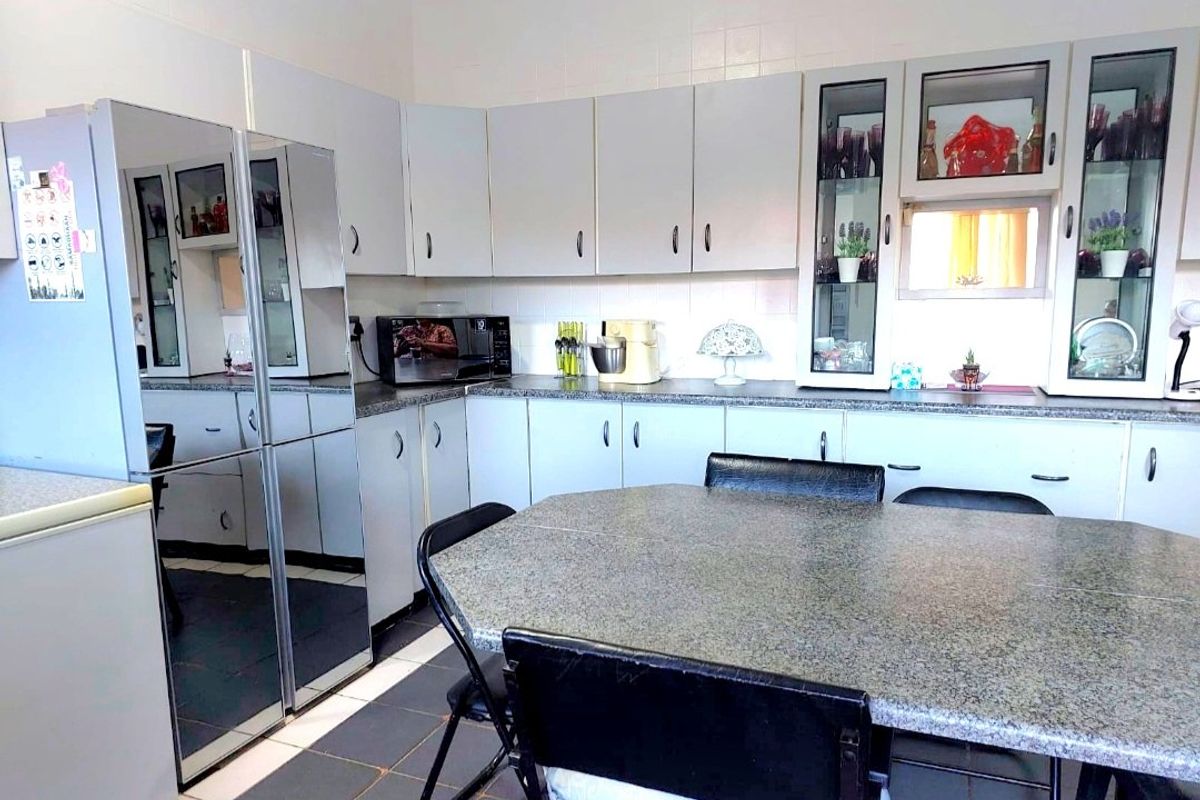 A functional kitchen featuring light-toned cabinetry, granite-look laminate countertops, tiled backsplash, and tiled flooring with integrated display cabinets.