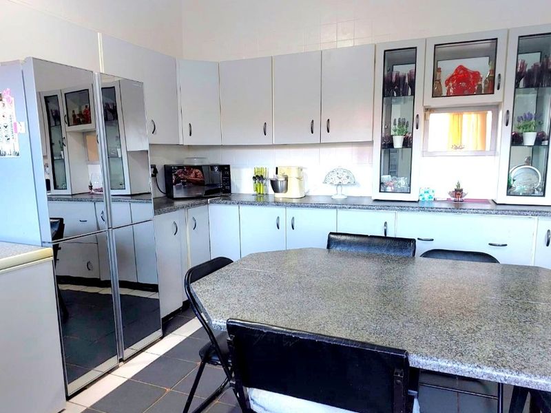 A functional kitchen featuring light-toned cabinetry, granite-look laminate countertops, tiled backsplash, and tiled flooring with integrated display cabinets.