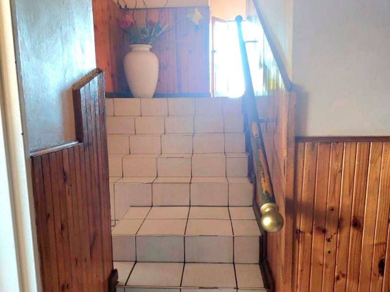 A staircase featuring tiled steps and timber wall paneling leading to an arched doorway.