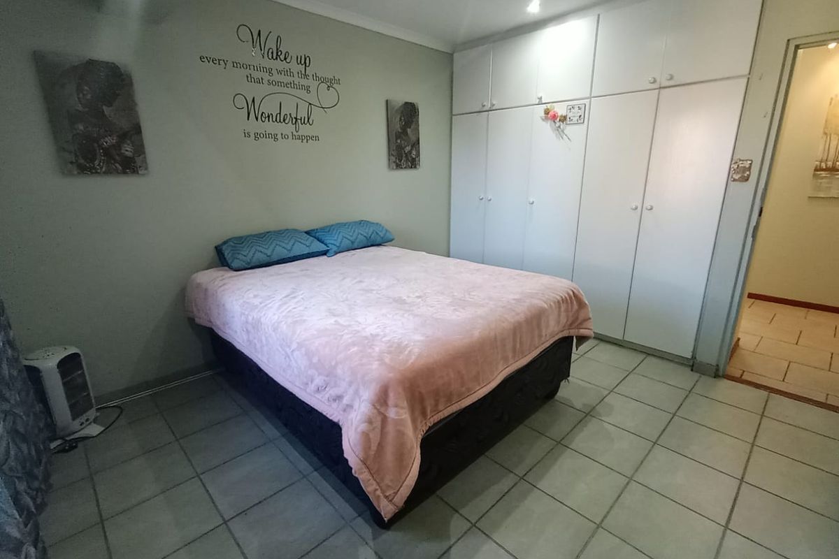 A bedroom featuring built-in floor-to-ceiling cupboards and tiled flooring, providing functional storage space.