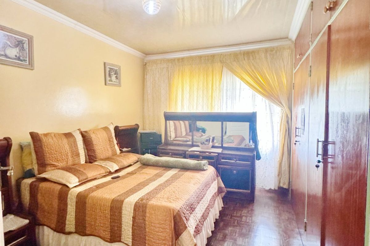 A bedroom featuring built-in wooden cupboards, parquet flooring, and crown molding, offering a functional and traditional living space.