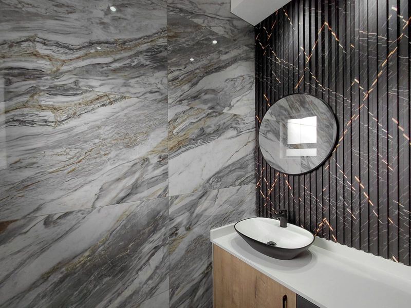 Modern bathroom featuring a sleek vessel sink, stone-look wall tiles, and a decorative slatted feature wall with integrated lighting.